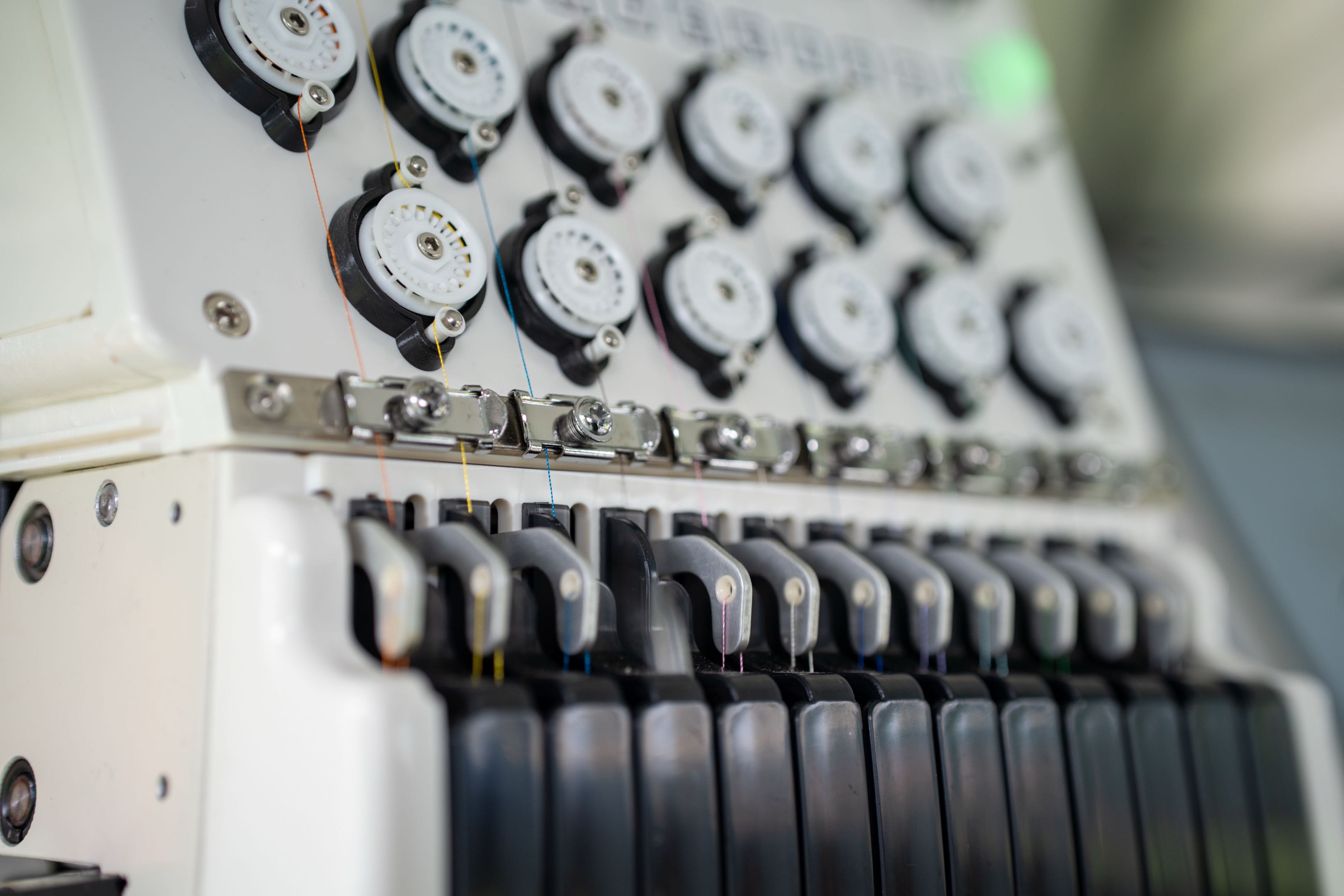 Tension dials and threads on the PrintStitch commercial embroidery machine
