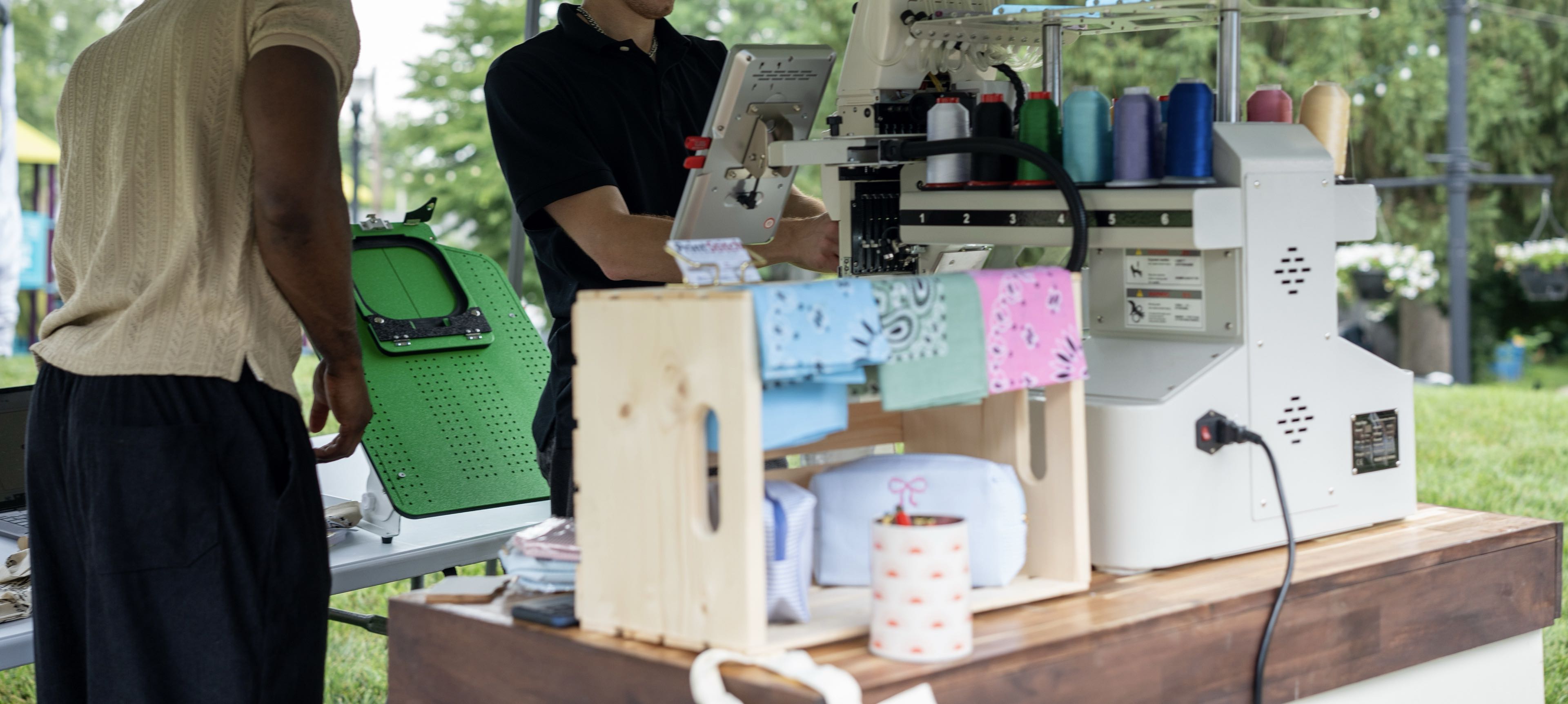 The PrintStitch team running the live embroidery cart on site at Solara Markets